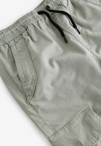 Lichtgrijze shorts met een elastische tailleband en zwarte trekkoord. Beschikt over twee zijzakken en een gestructureerde stof. Casual ontwerp.
