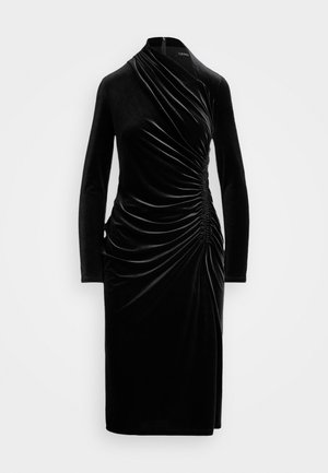Robe en velours noir à manches longues avec un design drapé, comportant des fronces sur le côté et une silhouette ajustée et élancée. Fermeture éclair dans le dos.