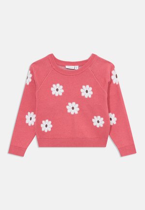 Rosa strikket genser med rund hals, pyntet med hvite blomsterapplikasjoner med svarte sentre, ribbede mansjetter og nederkant.