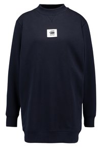 Mörkblå sweatshirt gjord av mjukt tyg, med rundad halsringning, långa ärmar, ribbade mudd och en fyrkantig logotypapplikation på framsidan.