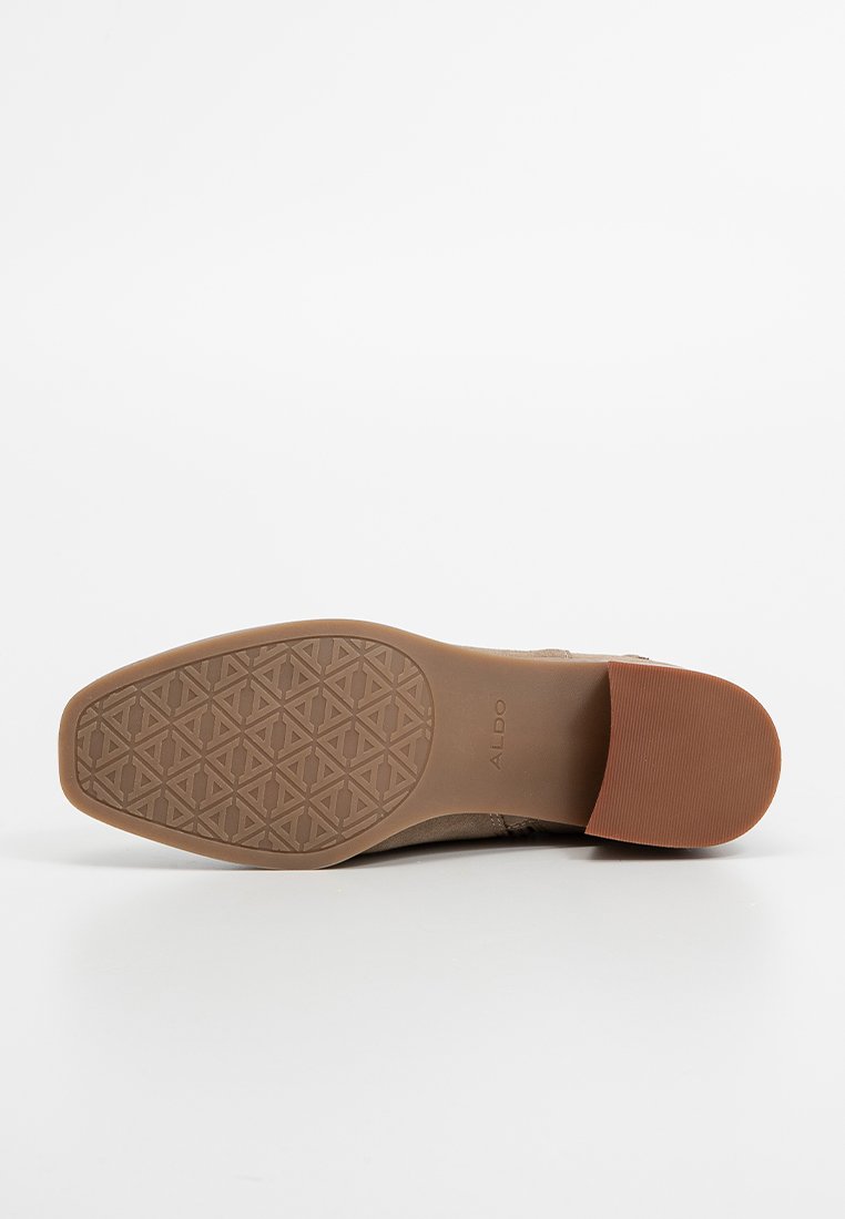 Semelle de chaussure synthétique marron avec un motif en losanges texturé, des accents en caoutchouc et un léger talon surélevé. Nom de la marque "Aldo" visible.