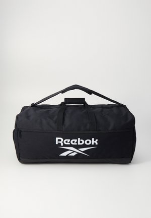 Svart duffelbag laget av slitesterkt stoff, med topphåndtak, glidelåslomme og stor hvit "Reebok"-logo på siden.