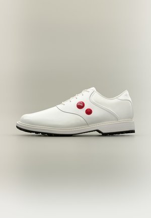Baskets en cuir blanc avec lacets, présentant deux boutons de pompe rouges sur le côté et une semelle noire texturée, vues de profil.