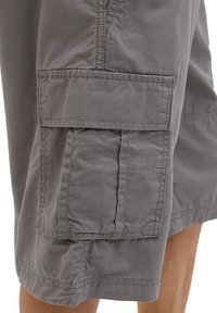 Gray cargo shorts featuring large side pockets, soft cotton material, and visible stitching detail, with a relaxed fit and knee-length hem.