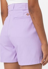 Lavendel shorts i bomull med hög midja, bakfickor och en liten varumärkesetikett på baksidan. Slät textur och skräddarsydd passform.