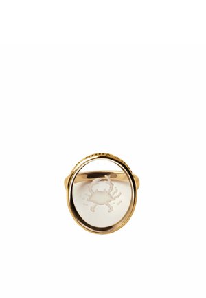 Anillo de oro con una piedra ovalada transparente que presenta un diseño grabado de un cangrejo en el centro, mostrado sobre un fondo blanco.