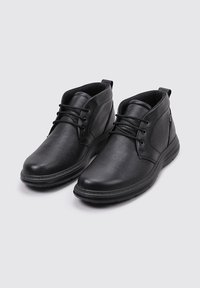 Botas de tobillo de cuero negro con un acabado texturizado, punta redondeada, cierre de cordones en la parte delantera y suela acolchada para mayor comodidad. Presenta acentos mínimos.