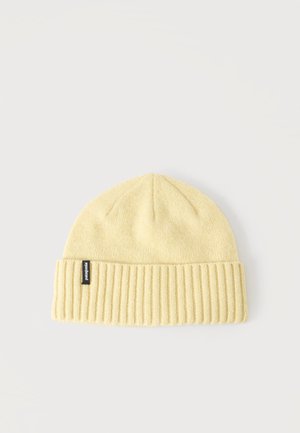 Gorro de punto amarillo claro con puño acanalado y una pequeña etiqueta negra de la marca Patagonia en el lado izquierdo.