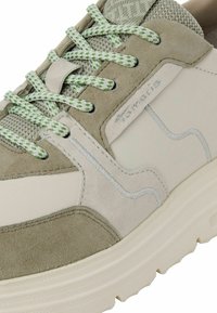 Ljusgrå och olivgrön sneaker med paneler av mocka och mesh, texturerade snören och en chunky, ljus sula. Har en diskret logotyp.