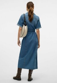 Jeanshemdkleid mit kurzen Ärmeln, Taillenkordelzug und Seitennähten. Kombiniert mit einer Umhängetasche und kniehohen braunen Stiefeln, zeigt es einen lässigen Stil.