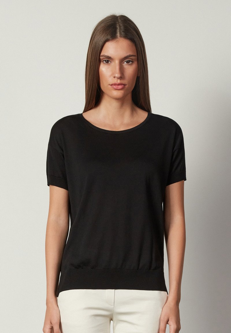 Svart kortärmad topp med rund halsringning och åtsittande fåll. Tillverkad av ett slätt, lätt tyg. Avslappnad och minimalistisk design.