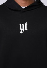Felpa nera con cappuccio realizzata in tessuto morbido, caratterizzata da un logo "yt" bianco stampato sulla parte anteriore, progettata con una vestibilità standard e cappuccio elasticizzato.