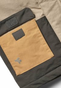 Grün-beigeJackenstoff mit einer auffälligen senfgelben Tasche. Verfügt über einen Klettverschluss und dezente Markenkennzeichnung in Grau. Glatte Textur.