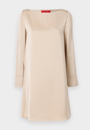 Beige satin dress with a square neckline, long sleeves, and a loose fit. Features a red brand label at the neck. Smooth texture.