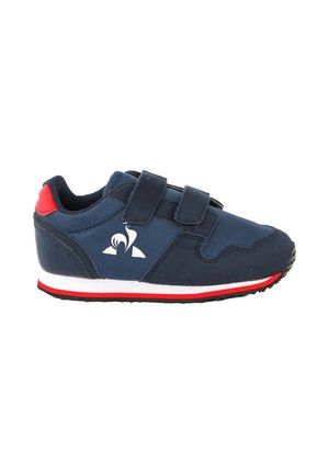 Zapatilla deportiva azul marino con dos tiras de velcro, suela blanca y roja, acento rojo en el talón y logo estilizado de pájaro blanco en el lateral.