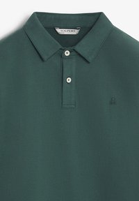 Polo de color verde oscuro, fabricado en un tejido suave, con un cuello clásico, tapeta de tres botones y un pequeño logotipo bordado en el pecho.
