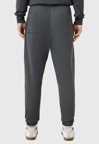 Szare bawełniane dresy z elastycznym pasem, ściągaczami na kostkach i dwoma naszytymi kieszeniami z tyłu. W zestawie z białymi sneakerami.