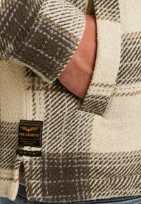 Geruite flanellen jas in tinten van crème, bruin en grijs, met een gestructureerde weving en een ingebed label nabij de zoom.