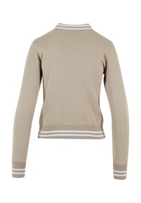 Beige hosszúujjú dzseki bordás gallérral, fehér csíkokkal. Puha tapintású, cropped fazonú, elasztikus mandzsettákkal és aljjal.