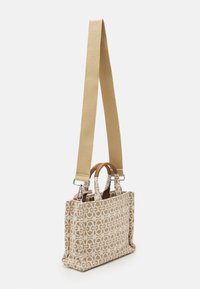 Textured fabric bag in beige with a geometric pattern, featuring a woven strap and dual top handles for versatile carrying options.