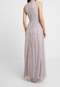 Langes mauvefarbenes Kleid mit einem Pailletten-Oberteil, transparentem Tüllrock mit verstreuten Verzierungen und einem taillierten Rückendesign.