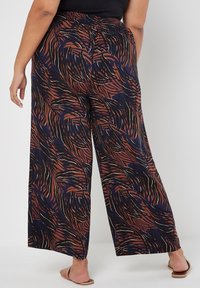 Weite Hosen aus einem gemusterten Stoff in Brauntönen und Marineblau, mit einem gerafften Bund und fließendem Design, geeignet für die Freizeit.