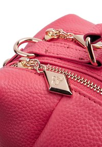Borsa a mano in pelle rosa con superficie testurizzata, hardware dorato e un charm decorativo sulla cerniera.