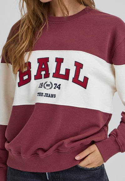 Pullover color bordeaux e crema con il bold "BALL" e l'anno di fondazione 1974. Disponibile con maniche a coste e una finitura in tessuto texturizzato.
