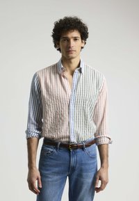 Camisa a rayas con colores pasteles alternos; rosa y blanco a la izquierda, gris y verde a la derecha. Cuello abotonado y mangas dobladas.