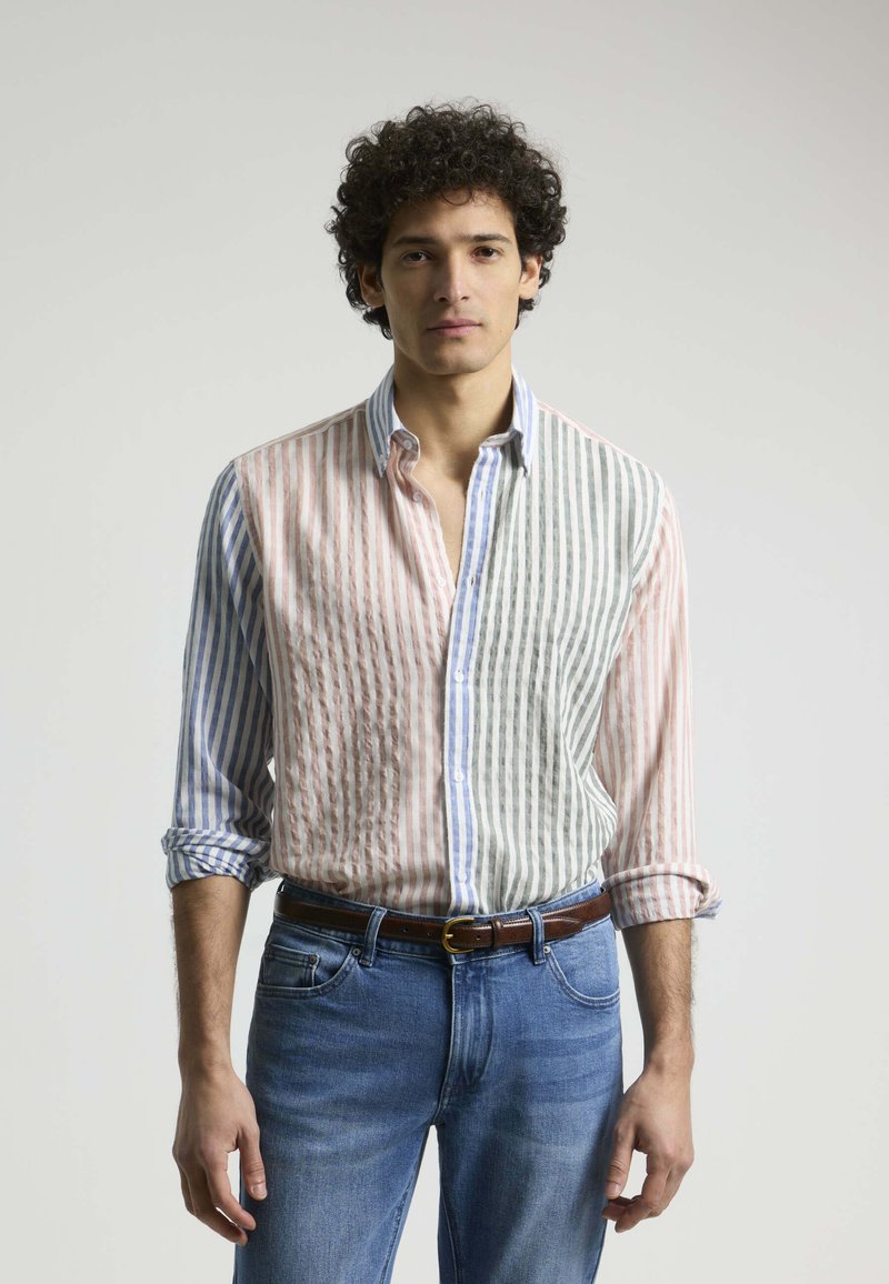 Camisa a rayas con colores pasteles alternos; rosa y blanco a la izquierda, gris y verde a la derecha. Cuello abotonado y mangas dobladas.