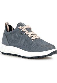 Chaussure de sport en tissu gris foncé avec des accents gris clair, surface texturée, lacets plats et une semelle blanche épaisse avec un motif de semelle en caoutchouc.