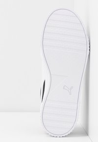 White sneaker with a textured rubber outsole, featuring black accents and a sleek profile. Notable logo on the side, minimalistic design.