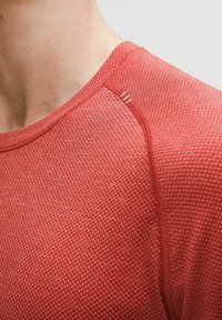 Bluză roșie cu mâneci scurte, cu un model texturat, decolteu rotund și cusături contrastante pe umăr. Material ușor și respirabil.