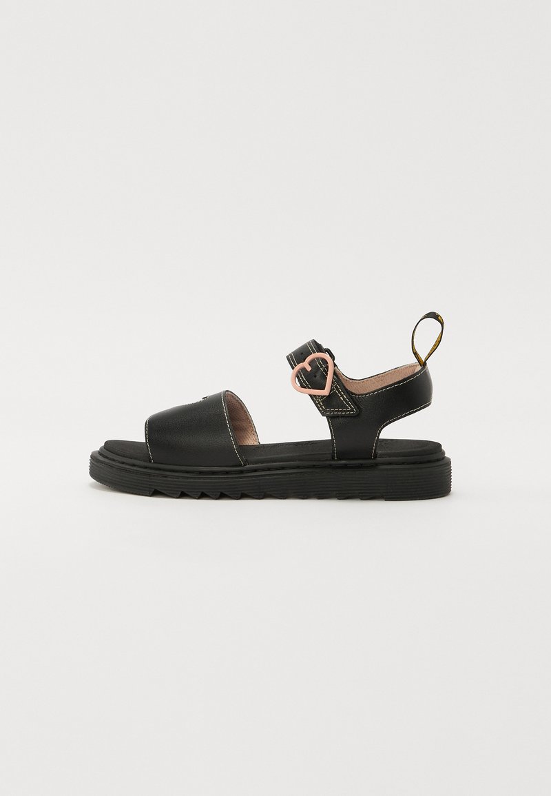 Sorte skinnsandaler med flat såle, åpen tå, justerbar rem med hjerteformet dekorasjon, samt beige sømdetaljer.