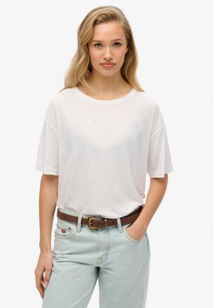 Lyserød kortærmet T-shirt lavet af blødt stof, med rund halsudskæring og afslappet pasform, parret med lys denim og et brunt bælte.