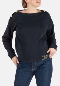 Schwarzes Sweatshirt mit weitem Ausschnitt, langen Ärmeln, dekorativen goldenen Knöpfen an der Schulter und gesticktem goldenen Logo am Saum.
