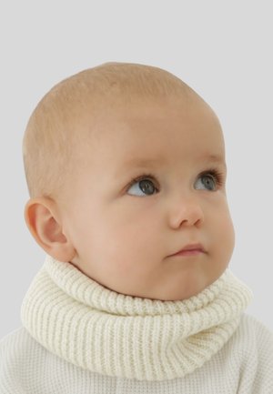 Knitted cream turtleneck with a chunky, ribbed texture. Close-up of a child's face, featuring round cheeks and wide blue eyes.