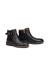 Bottines en cuir noir avec fermeture éclair sur le côté, détail de boucle et un talon bas robuste. Texture lisse avec une doublure intérieure brun contrastante.