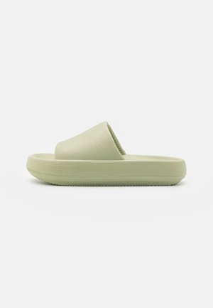 Sandale à glissière vert clair avec une sangle texturée, semelle plate et bout rond. Design simple, fabriqué à partir d'un matériau flexible.