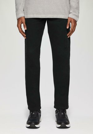 Zwarte cargo broek met een rechte snit, voorzien van zijzakken. Gecombineerd met zwarte sneakers en een lichtgrijze long-sleeve top.