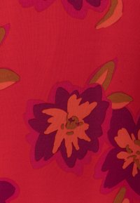 Rød stof med store lilla og orange blomster mønstre, der har en glat tekstur og dristige farvekontraster.