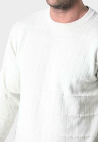 Biały sweter o fakturze, z ribbowanym wzorem w poziome i pionowe paski. Klasyczny okrągły dekolt i długie rękawy.