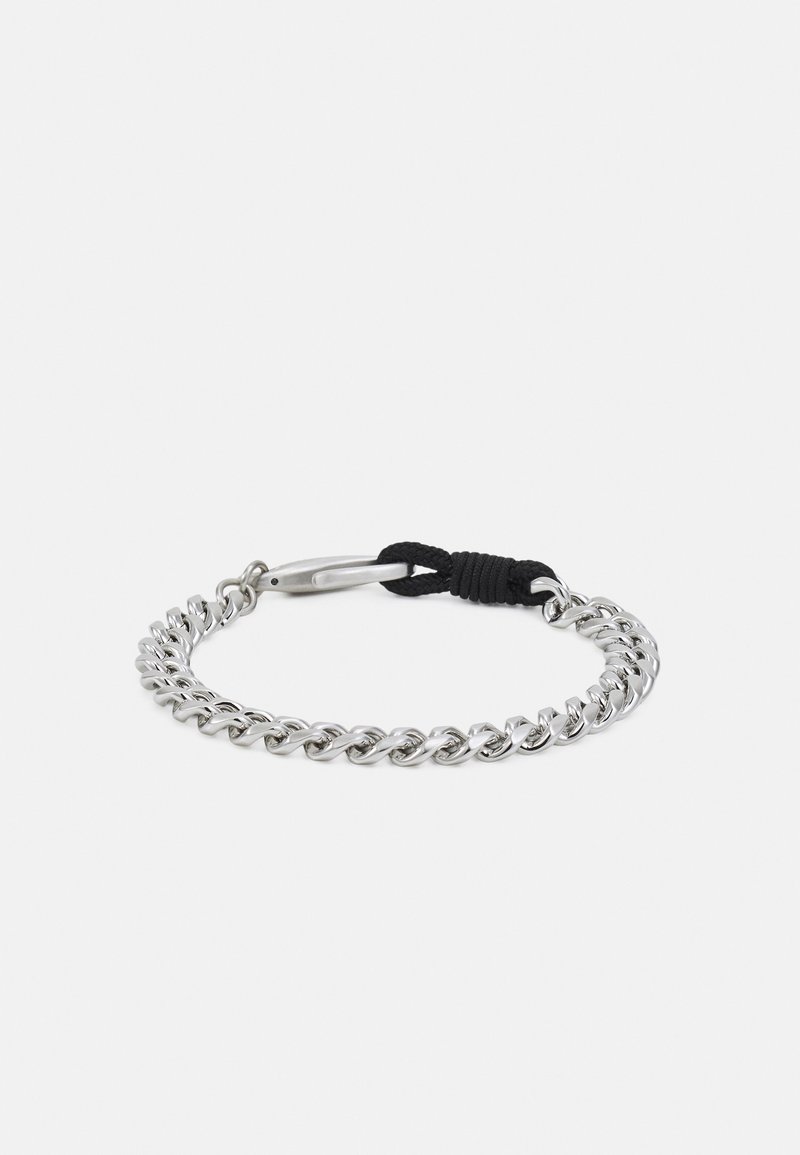 Bracelet chaîne en argent avec fermoir fixé par un cordon noir, exposé sur un fond blanc uni.