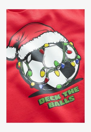 Punat punainen huppari, jossa on graafinen kuva jalkapallosta, joka korostuu joulupukin hatulla, koristeena värikkäitä joululyhtöjä ja teksti "DECK THE BALLS."
