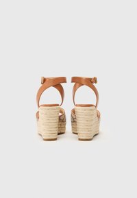 Sandale wedge din piele maro cu toc din sfoară espadrile, având o curea de gleznă sigură și un model texturat pe partea superioară.