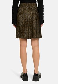 Gonna plissettata nera e marrone con stampa leopardata. Realizzata in tessuto leggero, presenta una vita alta e un design fluido.