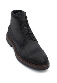 Botín de ante gris oscuro con puntera redondeada, parte superior con cordones y suela marrón en contraste. Presenta acentos de costura y una textura suave.