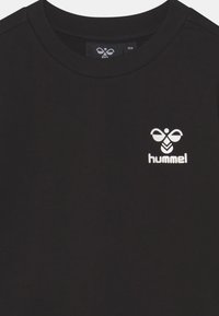 Crna pamučna majica s okruglim izrezom i bijelim Hummel logotipom na prsima. Mekan materijal, klasičan kroj i kratki rukavi.