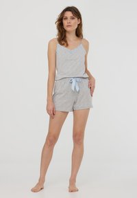 Set di pigiama grigio composto da una maglietta senza maniche con dettagli in pizzo e pantaloni corti con fantasia. I pantaloni corti hanno una cintura elastica con un fiocco blu.