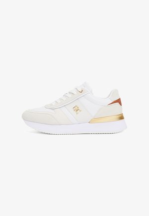 Witte sneakers van een mix van leer en suede, met gouden accenten op de hiel en het logo, textuur aan de zijkanten en een witte rubberen zool.